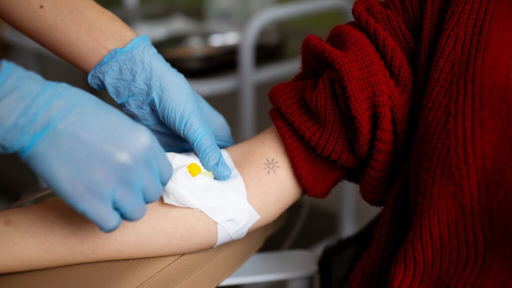 Chemotherapy for Blood Cancer in Thrissur showing a healthcare professional administering IV treatment to a patient’s arm in a clinical setting Caption: