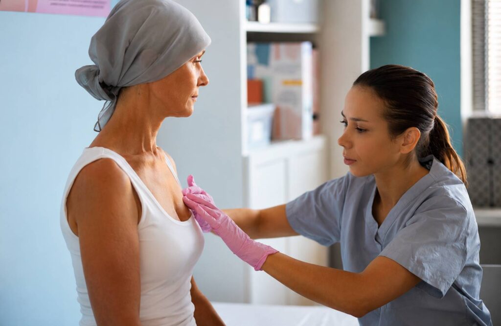 Breast cancer treatment in Thrissur consultation showing a healthcare professional performing a clinical breast examination for a patient in a modern medical setting.